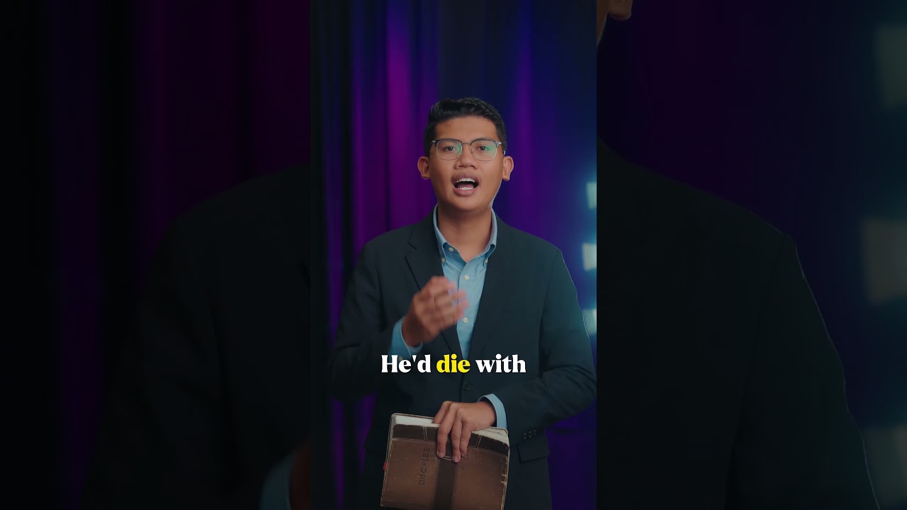 Thumbnail for the Short “The Cross Was Not an Accident” — a young man in a suit holding a book, speaking to camera