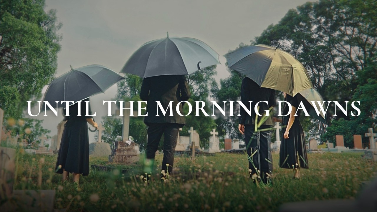Thumbnail for the music video &ldquo;Hope After Loss | Is Death Really the End?&rdquo; — mourners holding umbrellas stand among the graves beneath the words &lsquo;Until the Morning Dawns&rsquo;