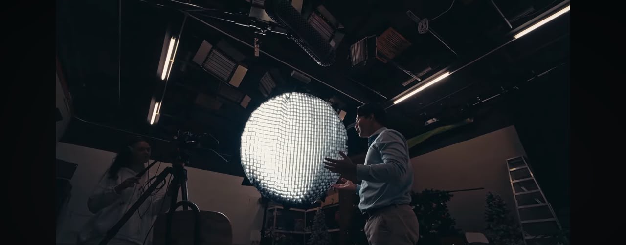 A volunteer sharing his story in the LoudVoice studio, standing before a large round studio light with a camera on a tripod nearby