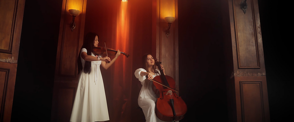 Violin and cello duet performing in warm amber light in a LoudVoice music video