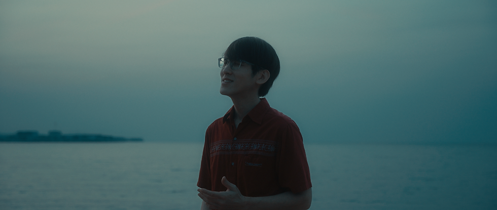 A young singer by the sea at dusk in a LoudVoice music video