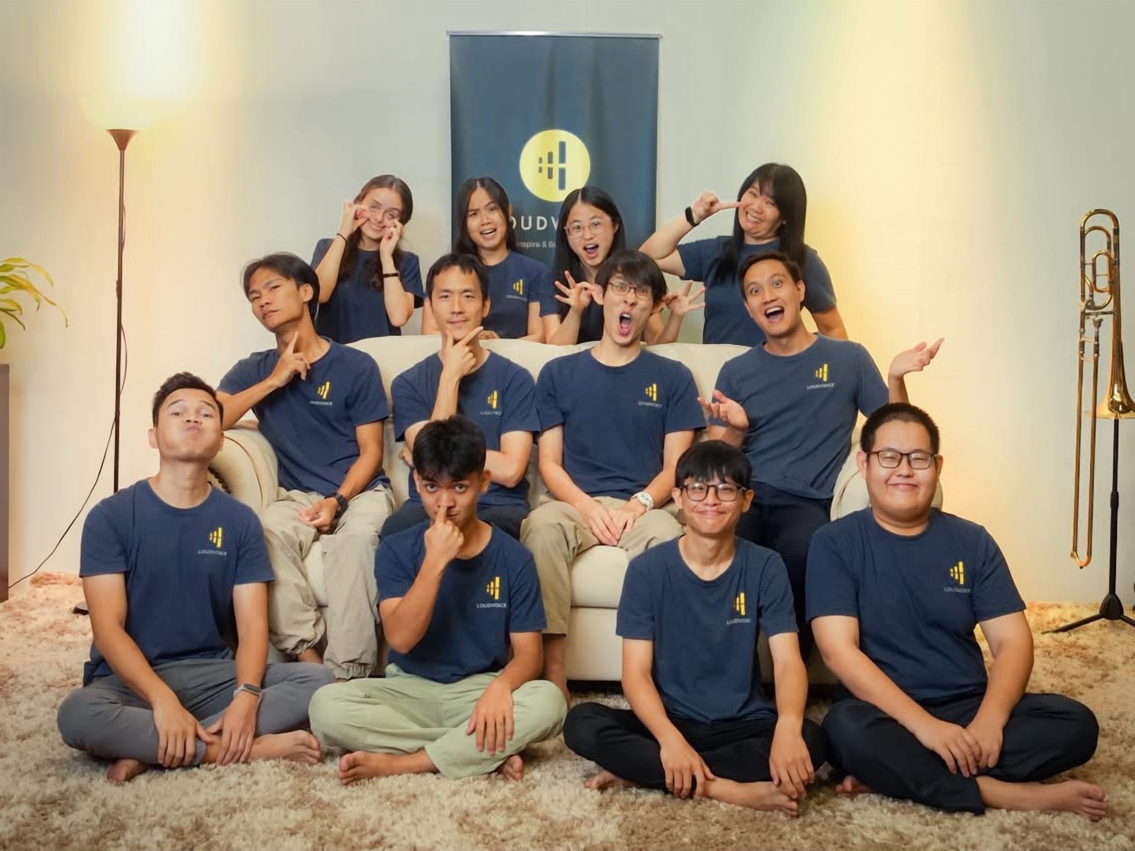 A candid group photo of the LoudVoice team in matching LoudVoice shirts, making funny faces, August 2025