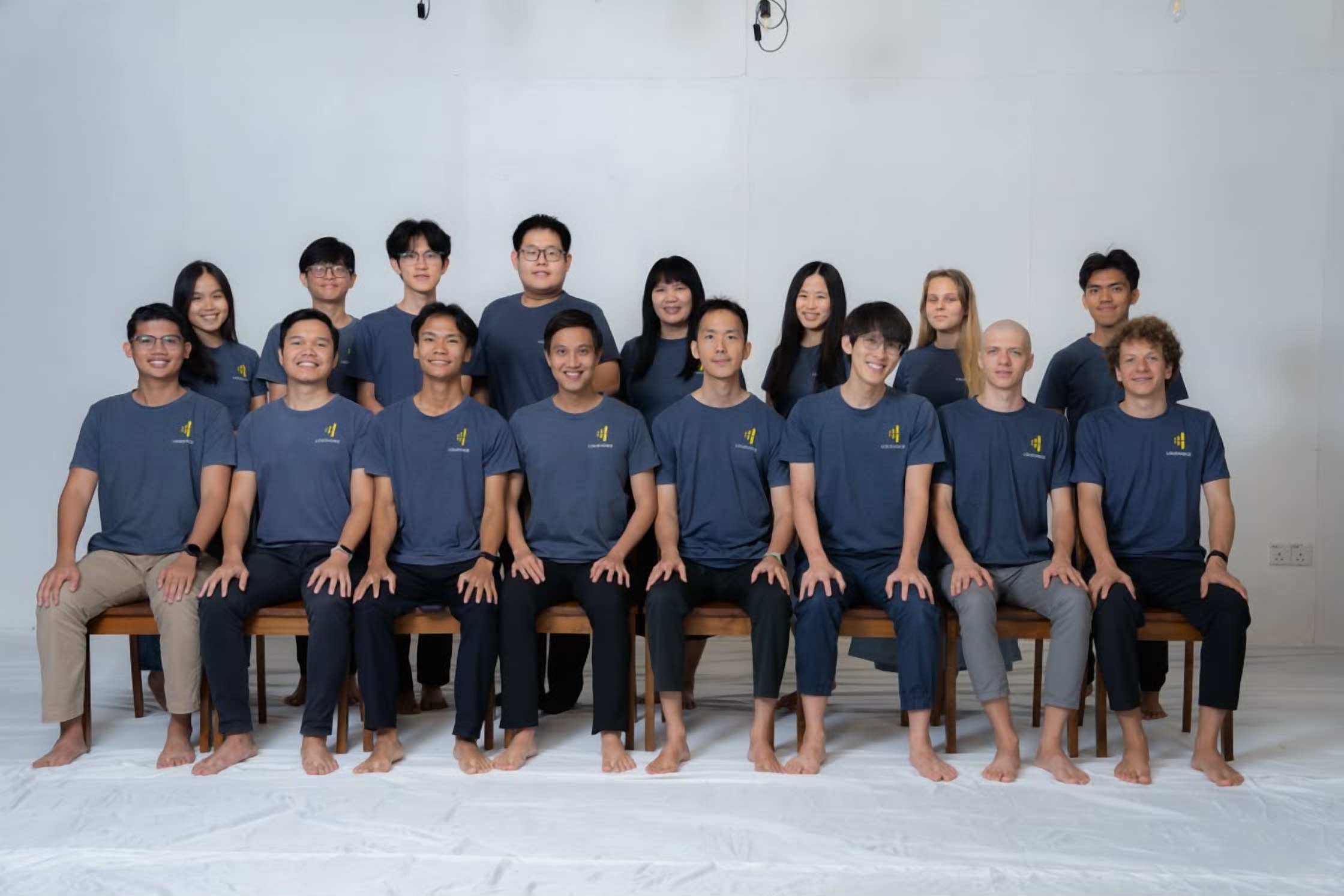 The LoudVoice team group photo from November 2025, sixteen members in matching LoudVoice shirts seated and standing in two rows against a white studio backdrop