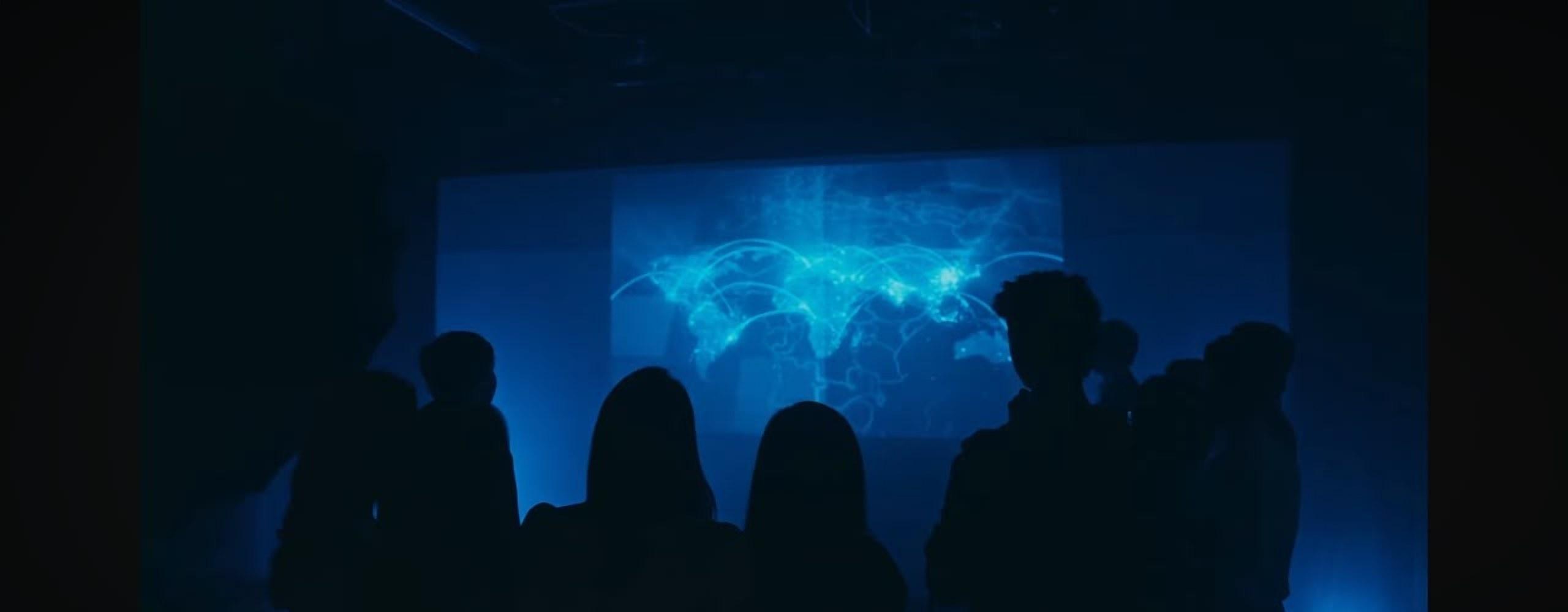Silhouettes of volunteers standing before a glowing world map